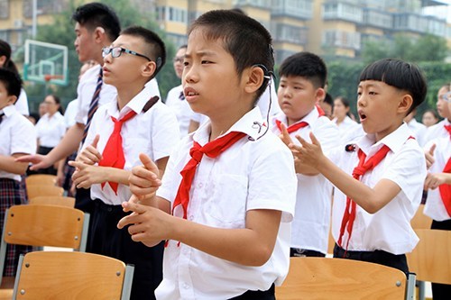 图为聋生在升国旗仪式上用国家通用手语表达国歌